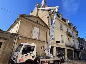 Camion nacelle Ent Maximoff bras déployé vers une souche de cheminée en centre-ville