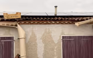 Gouttière descellée pendant le long d’une façade, avec des coulures d’eau sur le crépi